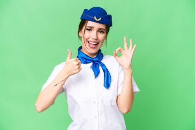 Airplane stewardess over isolated chroma key background showing ok sign and thumb up gesture
