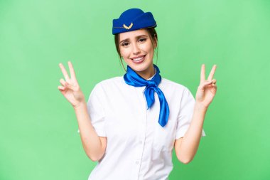 Airplane stewardess over isolated chroma key background showing victory sign with both hands