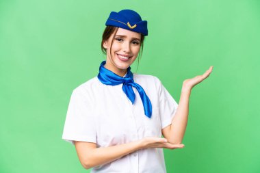 Airplane stewardess over isolated chroma key background extending hands to the side for inviting to come