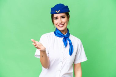 Airplane stewardess over isolated chroma key background shaking hands for closing a good deal