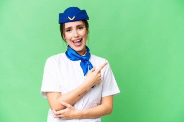 Airplane stewardess over isolated chroma key background surprised and pointing side