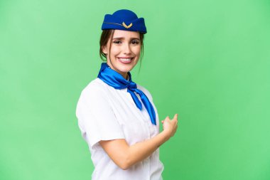 Airplane stewardess over isolated chroma key background pointing back