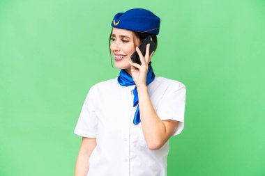Airplane stewardess over isolated chroma key background keeping a conversation with the mobile phone with someone