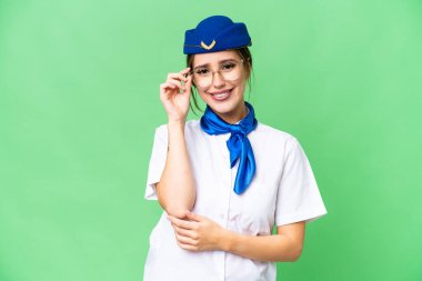 Airplane stewardess over isolated chroma key background with glasses and happy
