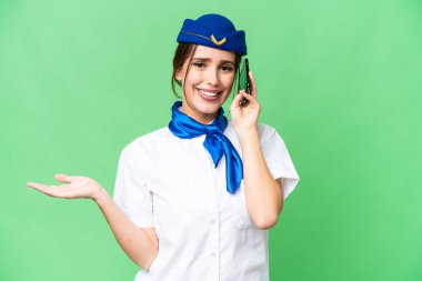 Airplane stewardess over isolated chroma key background keeping a conversation with the mobile phone with someone