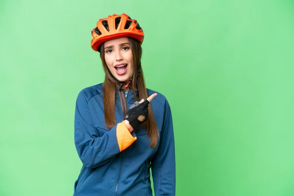 Young Cyclist Woman Isolated Chroma Key Background Surprised Pointing Side — Stockfoto