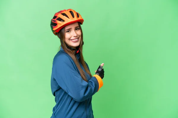 Young Cyclist Woman Isolated Chroma Key Background Pointing Back — Stockfoto