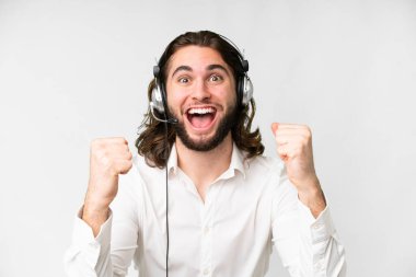 Telemarketer man working with a headset over isolated white background celebrating a victory in winner position
