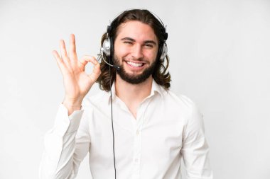 Telemarketer man working with a headset over isolated white background showing ok sign with fingers