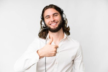 Telemarketer man working with a headset over isolated white background giving a thumbs up gesture