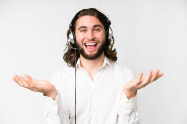 Telemarketer man working with a headset over isolated white background with shocked facial expression
