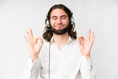 Telemarketer man working with a headset over isolated white background in zen pose