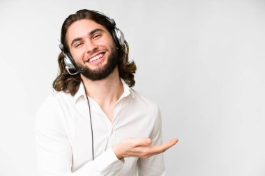 Telemarketer man working with a headset over isolated white background presenting an idea while looking smiling towards