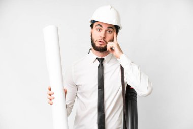 Young architect man with helmet and holding blueprints over isolated white background thinking an idea
