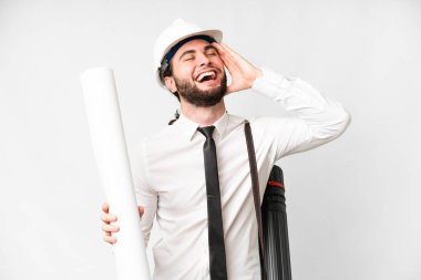 Young architect man with helmet and holding blueprints over isolated white background smiling a lot
