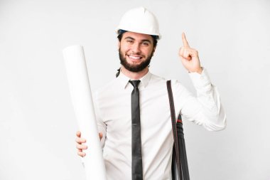 Young architect man with helmet and holding blueprints over isolated white background pointing up a great idea