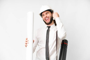 Young architect man with helmet and holding blueprints over isolated white background celebrating a victory