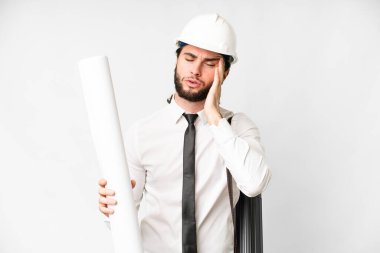 Young architect man with helmet and holding blueprints over isolated white background with headache