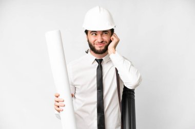 Young architect man with helmet and holding blueprints over isolated white background frustrated and covering ears