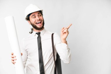 Young architect man with helmet and holding blueprints over isolated white background intending to realizes the solution while lifting a finger up