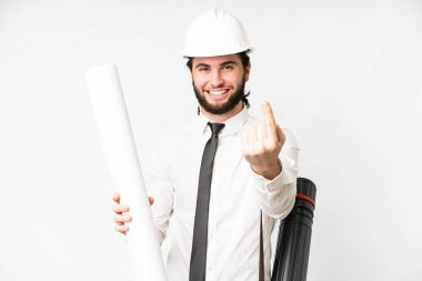 Young architect man with helmet and holding blueprints over isolated white background doing coming gesture
