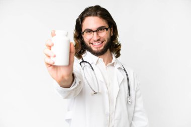 Genç, yakışıklı, soyutlanmış, beyaz bir geçmişi olan doktor önlüğü giyen ve elinde haplar tutan bir adam.