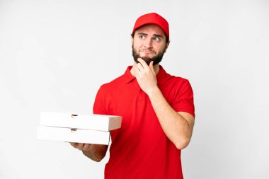 pizza delivery man with work uniform picking up pizza boxes over isolated white background having doubts and thinking