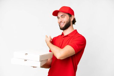 pizza delivery man with work uniform picking up pizza boxes over isolated white background pointing back