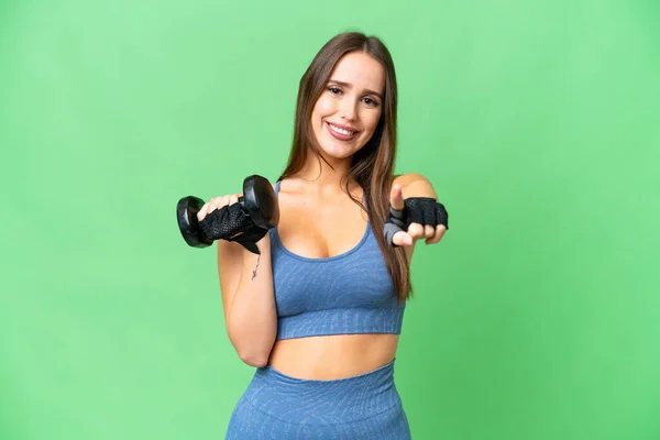 Young sport woman making weightlifting over isolated chroma key background points finger at you with a confident expression