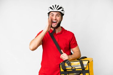Young delivery man with thermal backpack over isolated white background with surprise and shocked facial expression