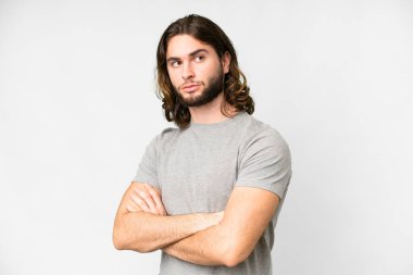 Young handsome man over isolated white background keeping the arms crossed