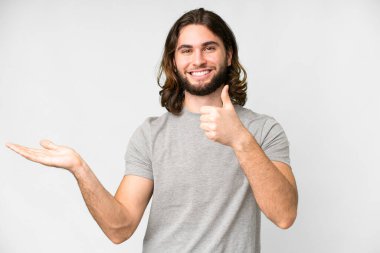 İzole edilmiş beyaz arka plan üzerinde genç yakışıklı bir adam. Avucunun içinde hayali bir şey tutuyor. Bir ilan vermek için.