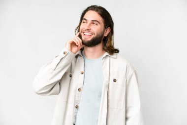 Soyutlanmış beyaz arka planda genç yakışıklı bir adam yukarı bakarken bir fikir düşünüyor.