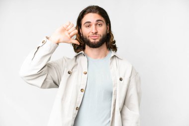 Soyutlanmış beyaz arka planda genç yakışıklı bir adam negatif ifadeyle baş parmağını aşağı gösteriyor.
