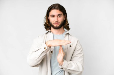 Soyutlanmış beyaz arka planda genç yakışıklı bir adam zaman aşımı hareketi yapıyor.