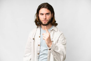 Soyutlanmış beyaz arka planda genç yakışıklı bir adam hayal kırıklığına uğramış ve ön tarafı işaret ediyor.