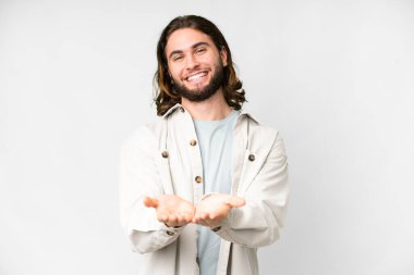 İzole edilmiş beyaz arka plan üzerinde genç yakışıklı bir adam bir ilan vermek için avucunun içinde hayali bir mekan tutuyor.