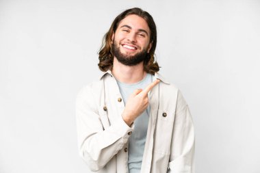 Soyutlanmış beyaz arka planda genç yakışıklı bir adam bir ürün sunmak için kenarı işaret ediyor.