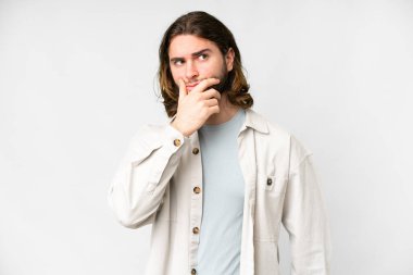 Soyutlanmış beyaz arka planı olan genç yakışıklı bir adam. Şüpheleri var ve kafası karışmış bir yüz ifadesi var.