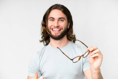 Genç yakışıklı, soyutlanmış beyaz bir arka plan ve mutlu bir ifadesi olan gözlüklü.