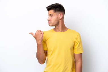 Beyaz arka planda izole edilmiş genç beyaz adam mutsuzdu ve kenarı gösteriyordu.