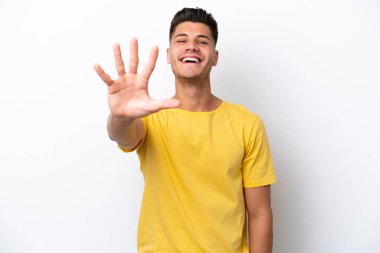 Beyaz arka planda izole edilmiş genç beyaz adam parmaklarıyla beşi sayıyor.