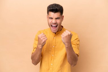 Beyazlı genç bir adam bej arka planda izole edilmiş. Kötü bir durum yüzünden hayal kırıklığına uğramış.