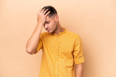 Beyazlı genç bir adam bej arka planda izole edilmiş baş ağrısı var.