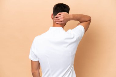 Beyazlı genç adam bej arka planda izole edilmiş ve düşünüyor.