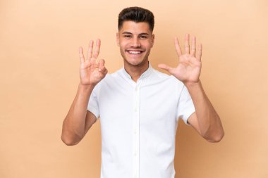Young caucasian man isolated on beige background counting eight with fingers