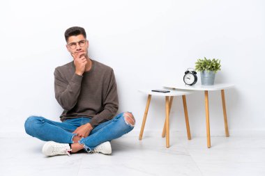 Beyaz arka planda soyutlanmış, evinde oturan genç, beyaz bir adam.