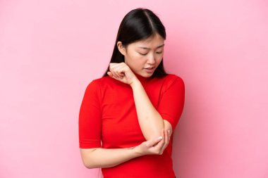 Young Chinese woman isolated on pink background with pain in elbow