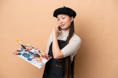 Young Chinese painter woman isolated on beige background proud and self-satisfied
