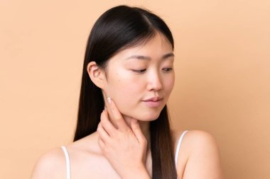 Genç Çinli kadın bej arka planda izole edilmiş. Portre